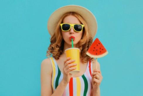 Τροφές και ηλιοπροστασία. Γυναίκα σε summer mood πίνει smoothie και κρατάει καρπούζι.