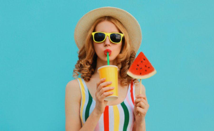Τροφές και ηλιοπροστασία. Γυναίκα σε summer mood πίνει smoothie και κρατάει καρπούζι.