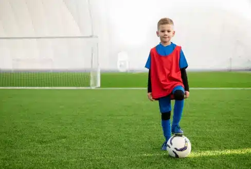 Μικρό αγόρι με στολή και μπάλα ποδοσφαίρου σε άρθρο για αθλητικές κακώσεις στα παιδιά