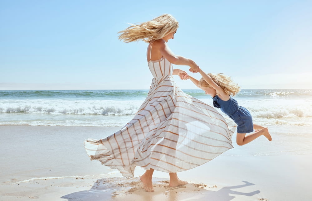 Γυναίκα και παιδί σε παραλία στον ήλιο σε άρθρο για αντηλιακή προστασία